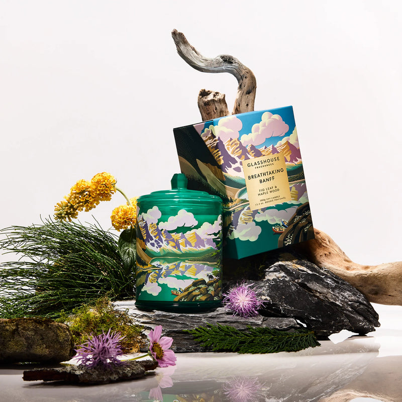 Candle with green decorative packaging on a natural setting with flowers and rocks